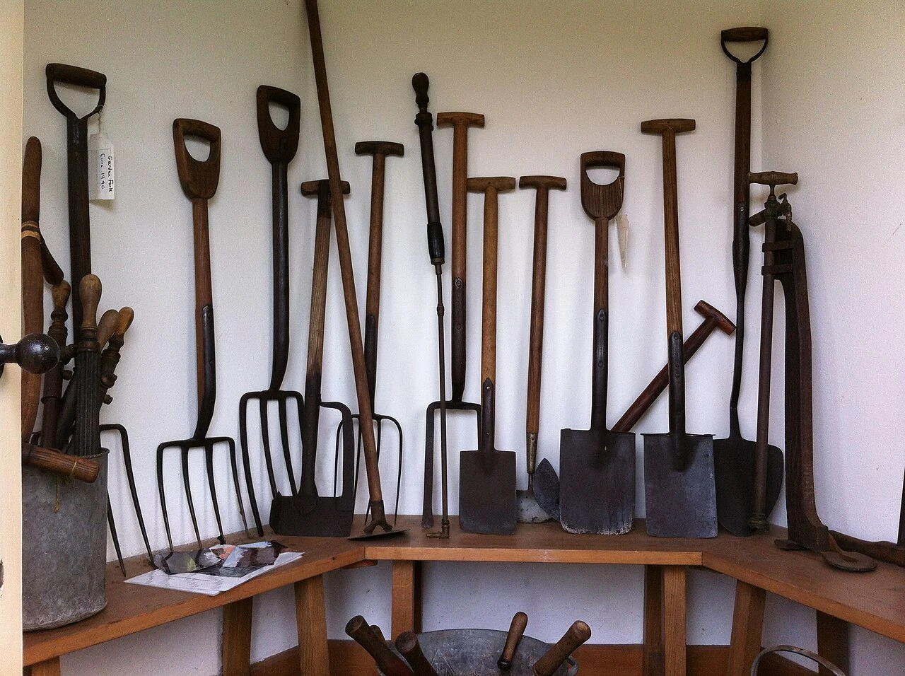 Spades, forks, and other garden tools hanging on a shed wall
