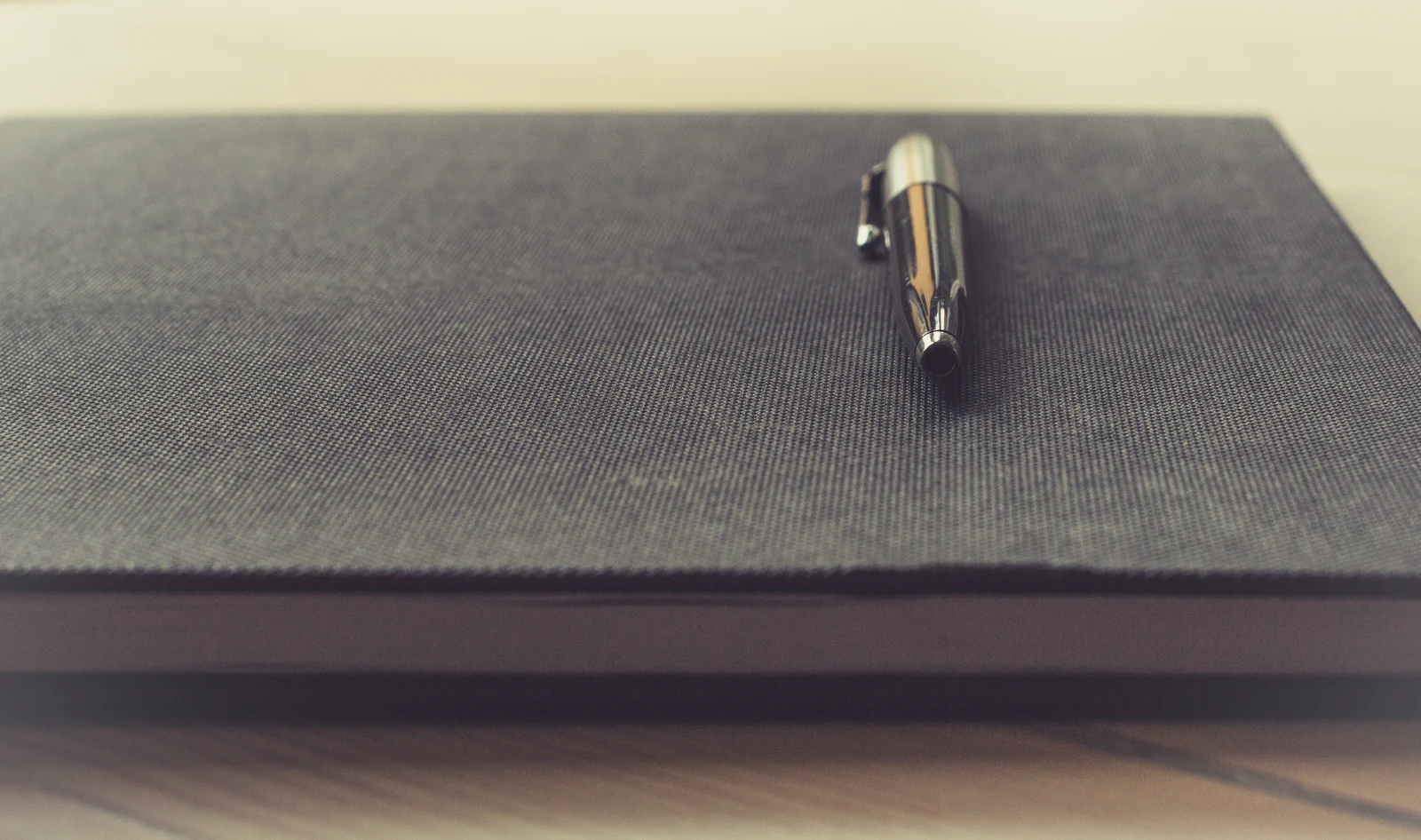 Pen on a closed notebook with a textured dark cover