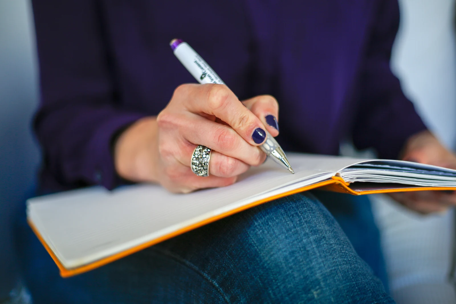 Hands holding a pen and writing in an open notebook